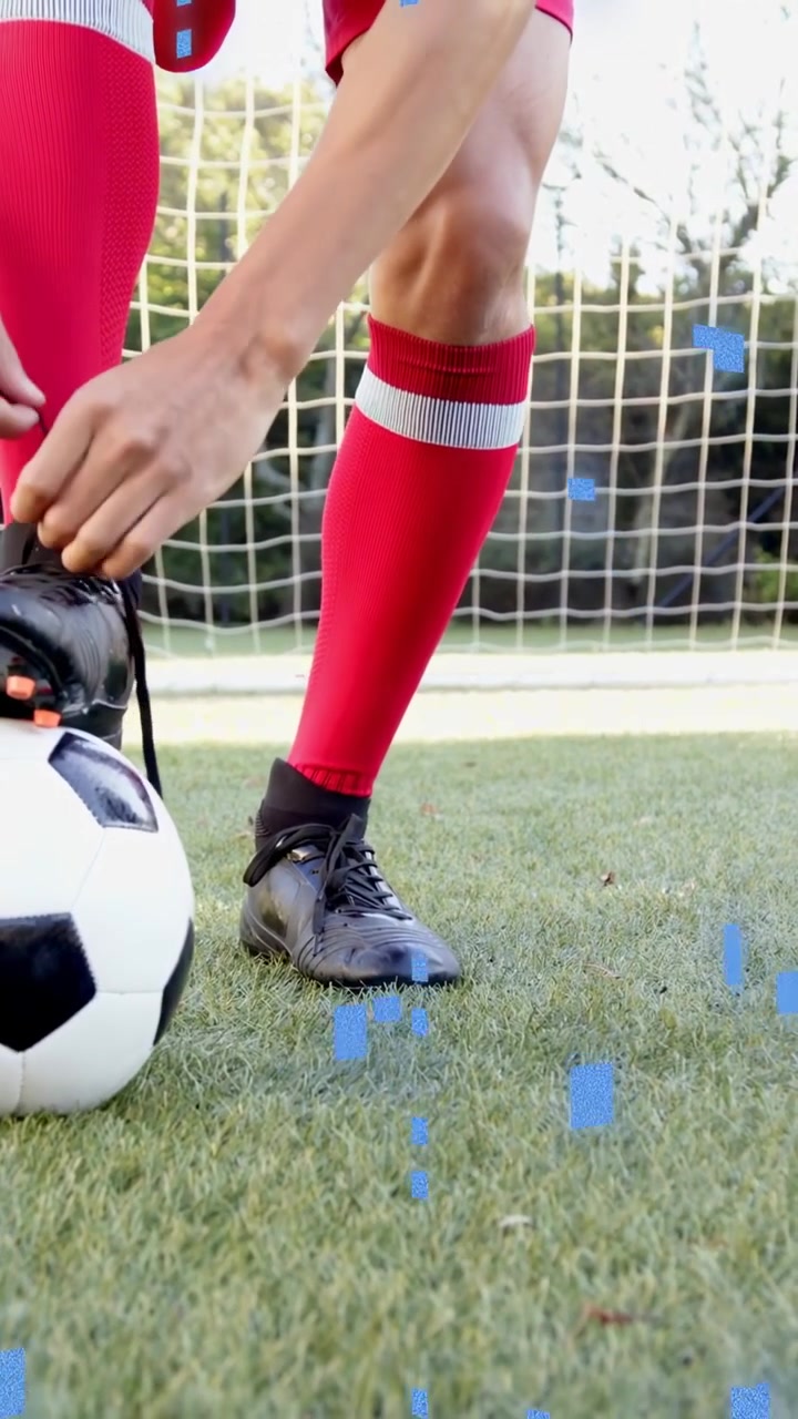Video vertical: Jugador dando toques al balón en el campo, notando un cordón suelto y atándolo, con cuadrados azules flotando.