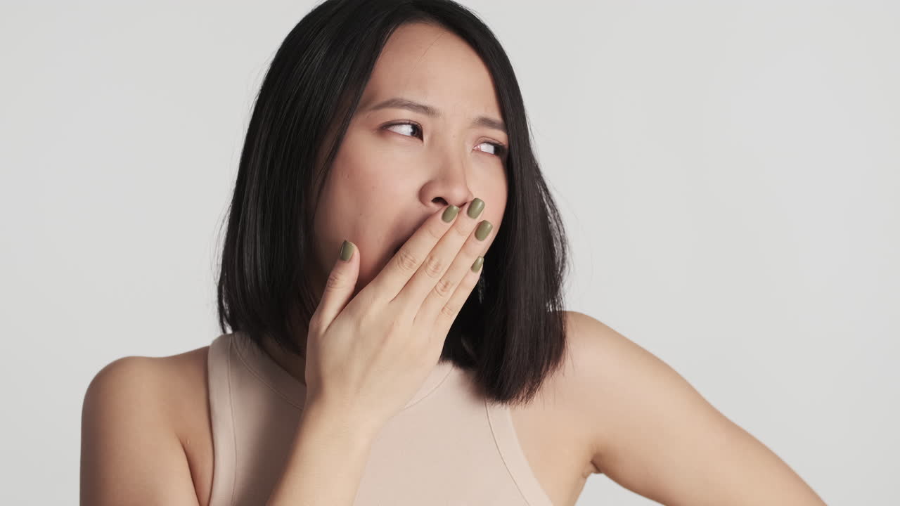 Tired Asian woman yawning on camera.