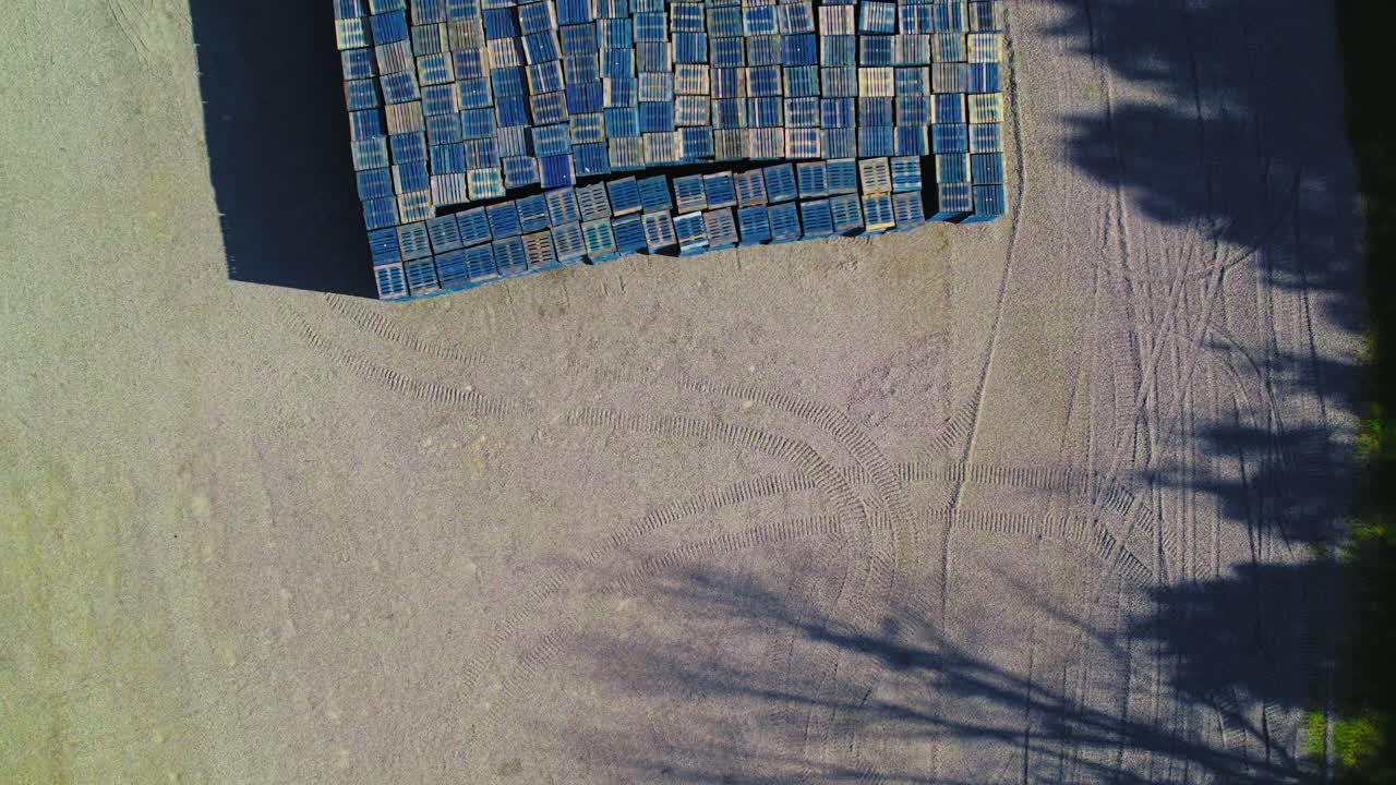 Top-Down Aerial View of Tightly Stacked Blue Wooden Pallets on Gravel Lot