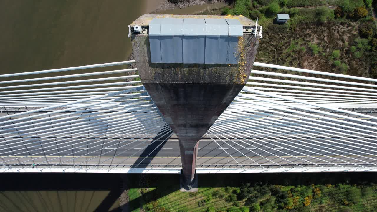 drone: puente colgante de pilón único mirando hacia abajo desde la parte superior de la estructura masiva al puente de abajo con el tráfico y el río que fluye por debajo del puente en waterford, irlanda.