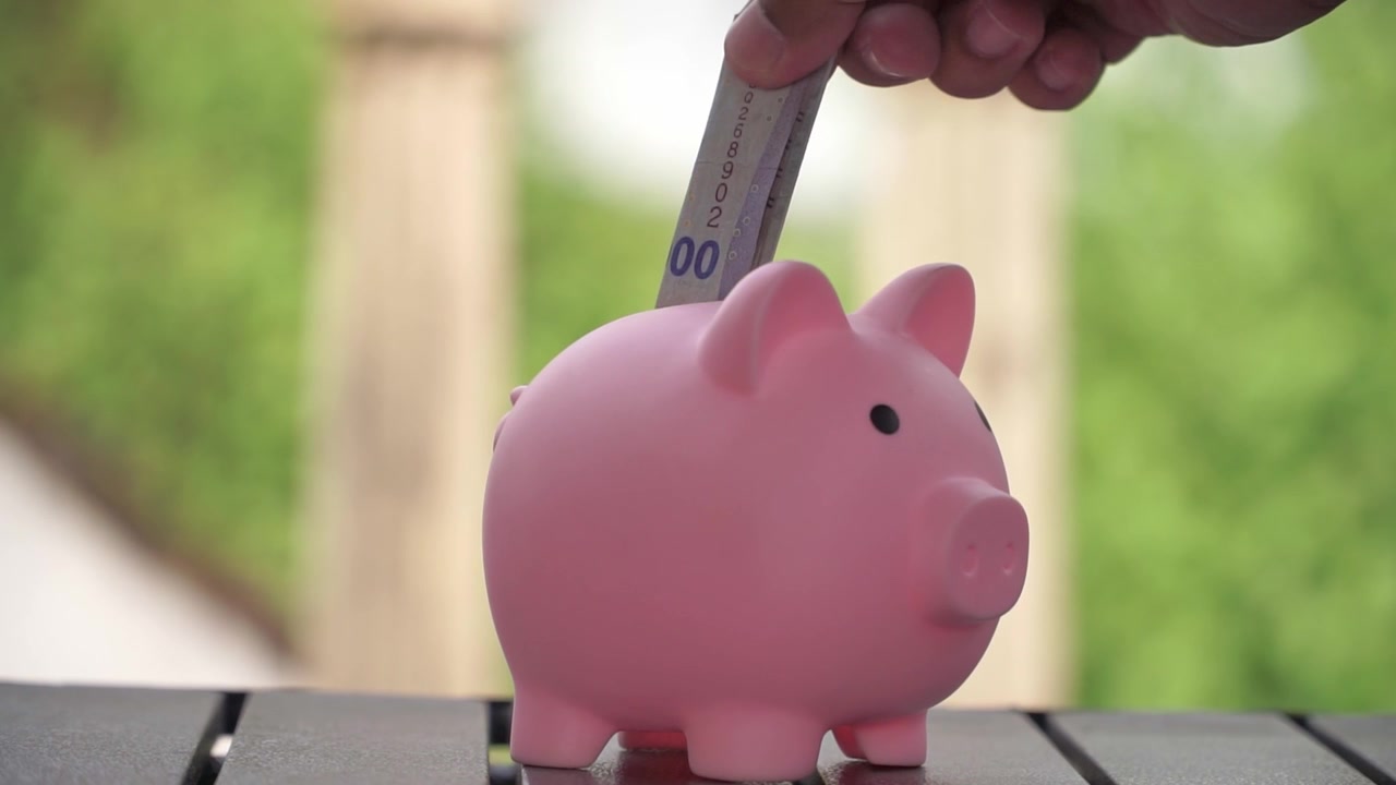 Hand of people inserting coin into piggy bank, symbol of smart saving, budgeting and financial security.