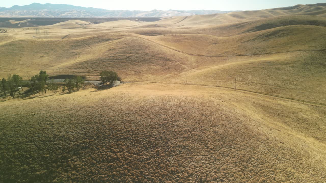 Dolly Zoom In Aerial drone view over San Luis Reservoir, capturing calm waters, rolling hills, and scenic landscapes in Merced County, California, USA, under a clear blue sky.