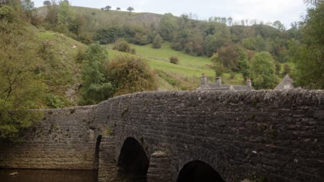 Side-wide-shot-of-stone-bridge-at-Wetton-mill-looking-east-and-at-the-valley-hillside-in-the-background