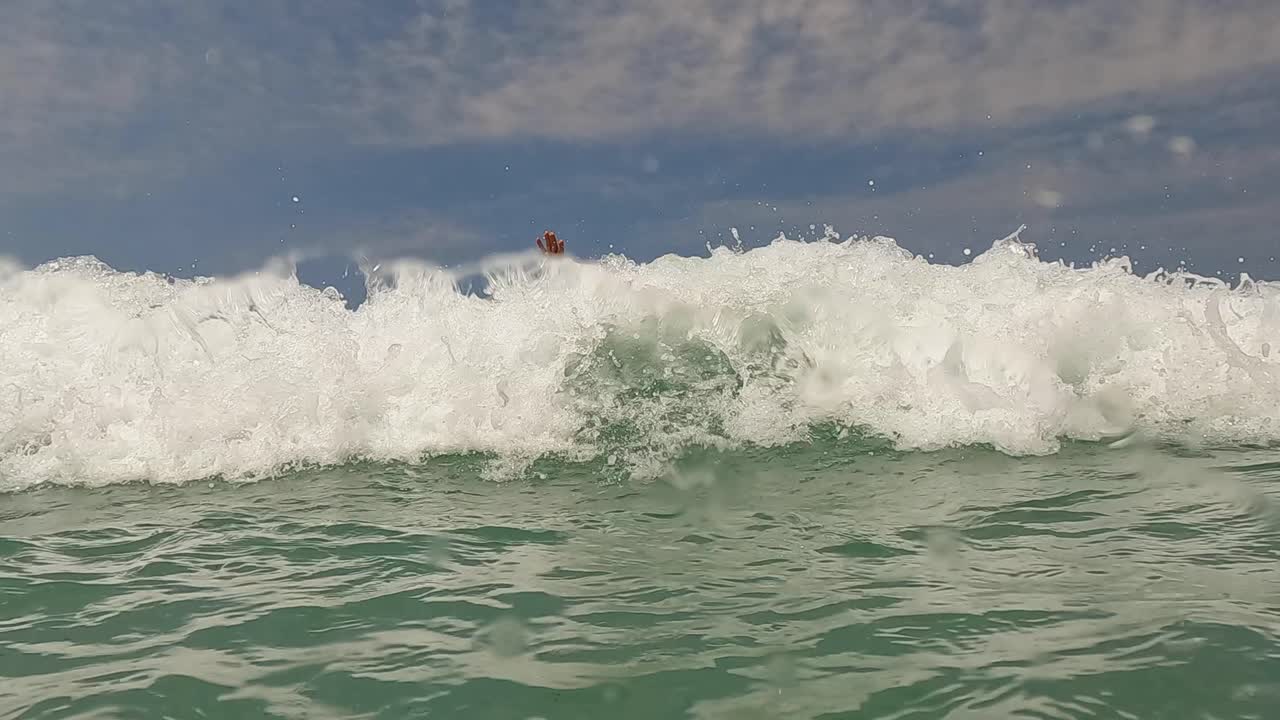팔을 활짝 벌리고 기다리는 큰 파도가 그에게 튀는 노인 수염이 있는 활동적인 남자의 물 표면 관점