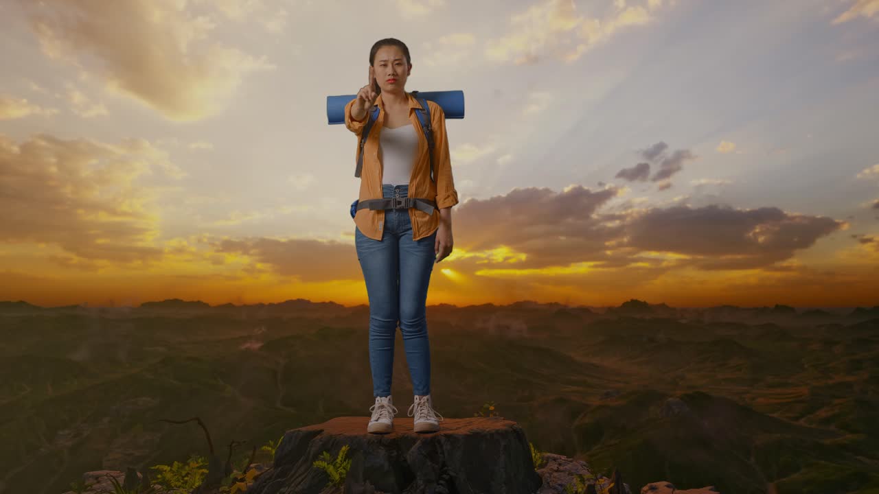 mujer excursionista mostrando el dedo medio en la cima de la montaña al atardecer