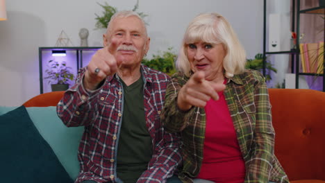 Senior-family-grandparents-man-woman-smiling-excitedly-and-pointing-to-camera,-choosing-lucky-winner