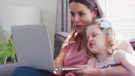 madre y hija caucásicas divirtiéndose usando una computadora portátil