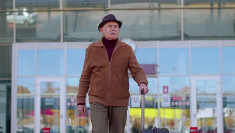 senior pensioner tourist grandfather businessman walking from airport hall gate with luggage bag