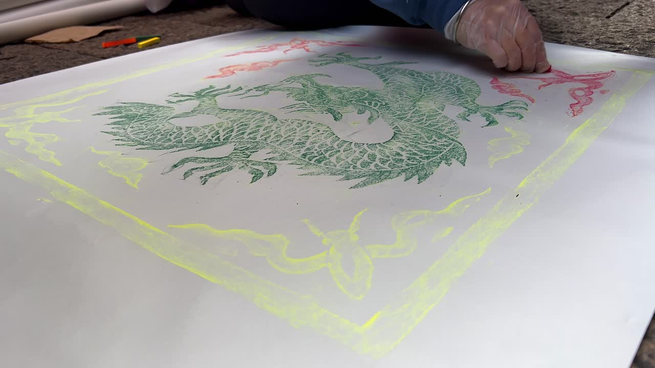 Un drago asiatico verde appare mentre un artista sfrega un tombino con del carbone