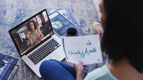 African-american-woman-holding-a-document-having-a-video-call-on-laptop-at-home