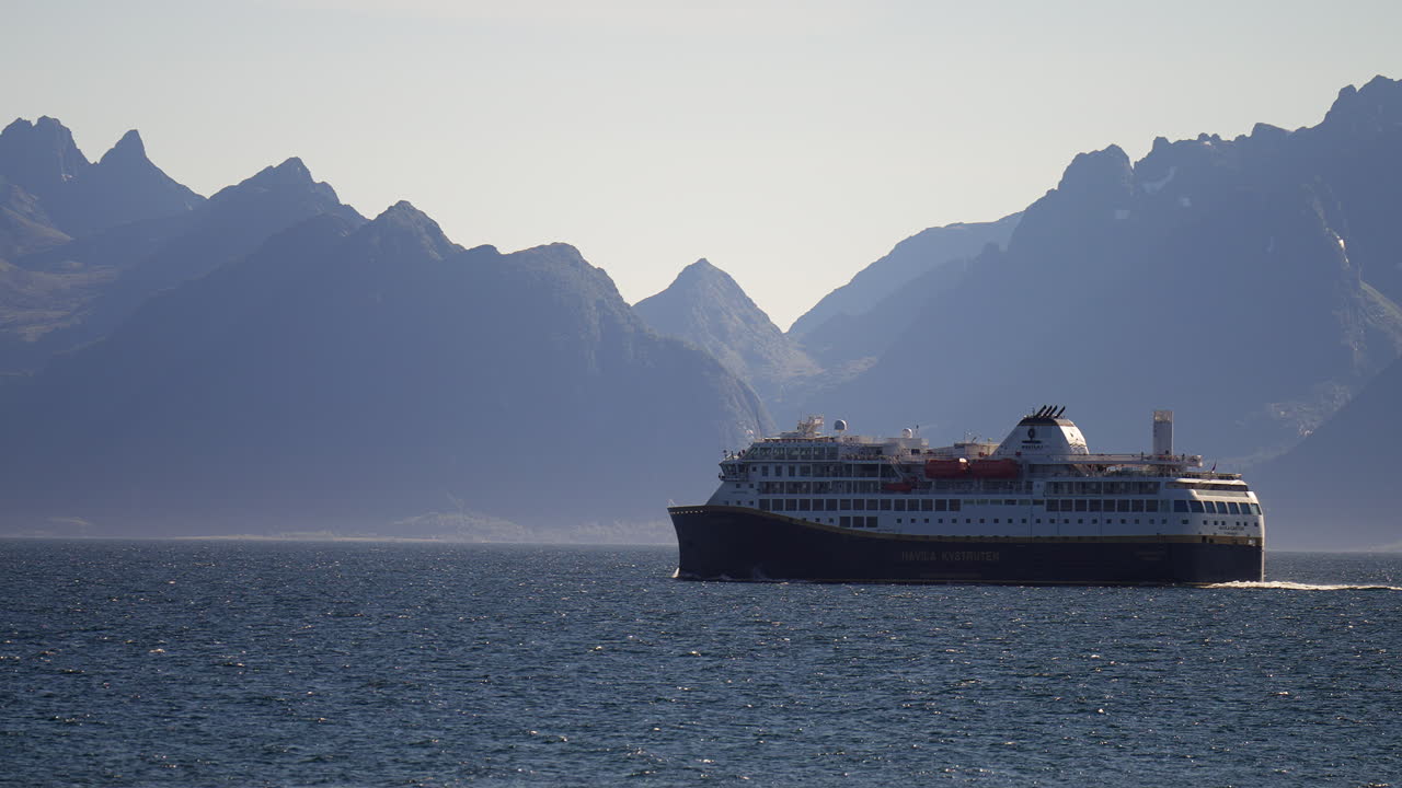 Færge sejler over roligt hav med Lofoten-bjergene i baggrunden