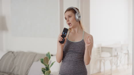 mujer joven feliz bailando firmando karaoke en casa usando auriculares celebrando con movimientos de baile divertidos divirtiéndose el fin de semana 4k