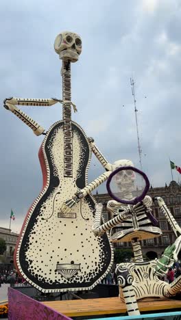 giant skeleton sculpture with guitar on display during day of the dead celebration, zócalo cdmx