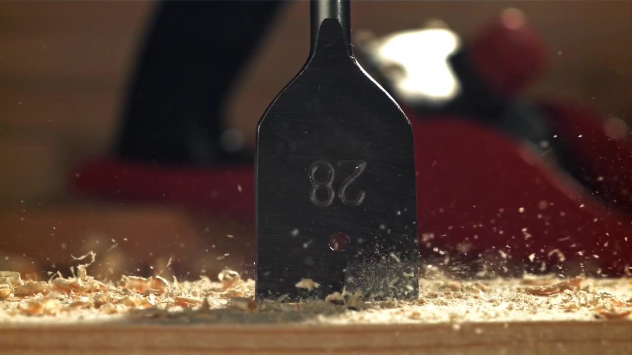 Slowmotion nærbillede af et spadebor, der borer ind i træ.