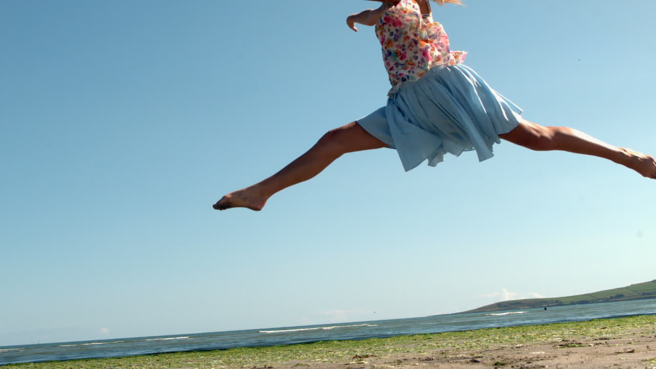 Gorgeous blonde doing ballet jump on beach