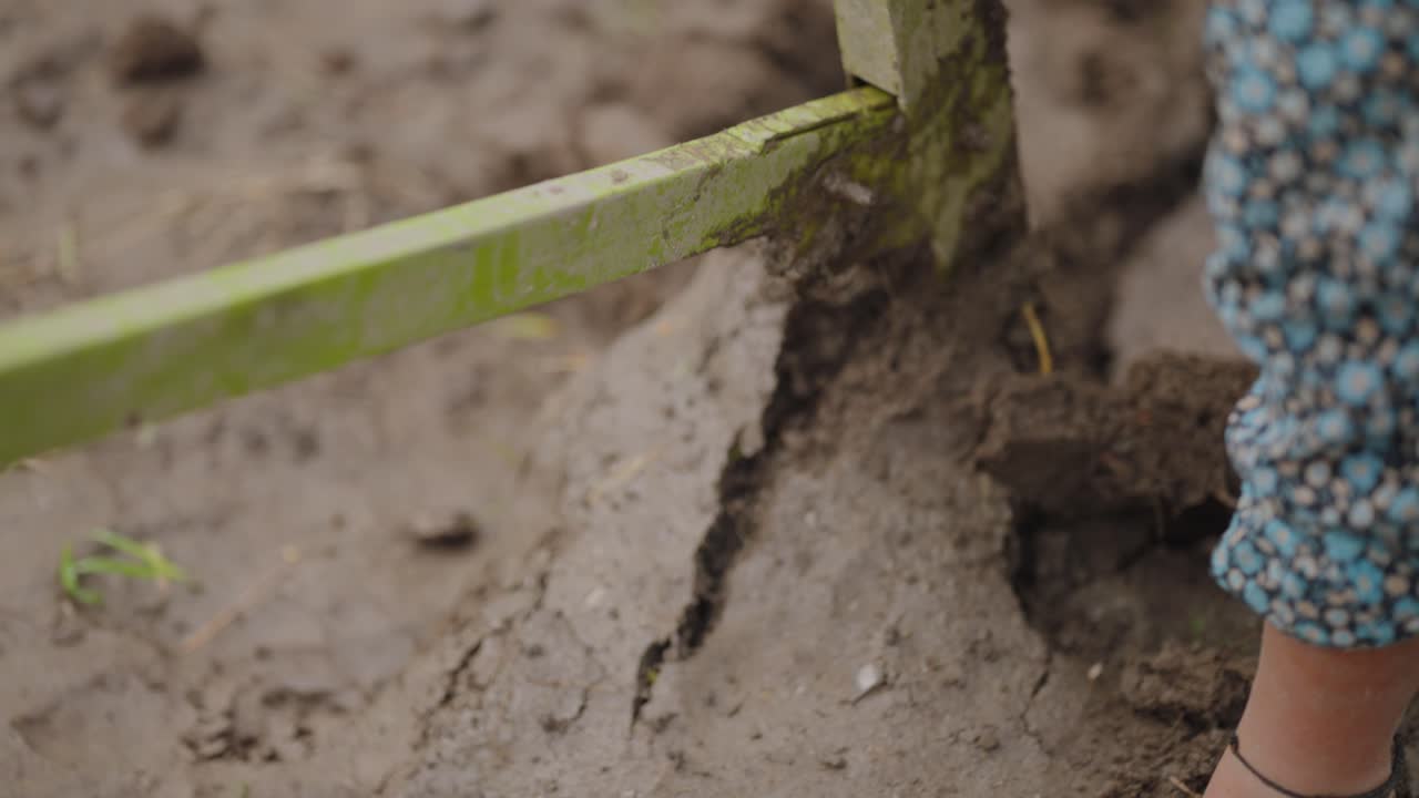Detail shot of metal plough blade cutting into parched earth, dust rising as it tills the dry farmland, 4k video