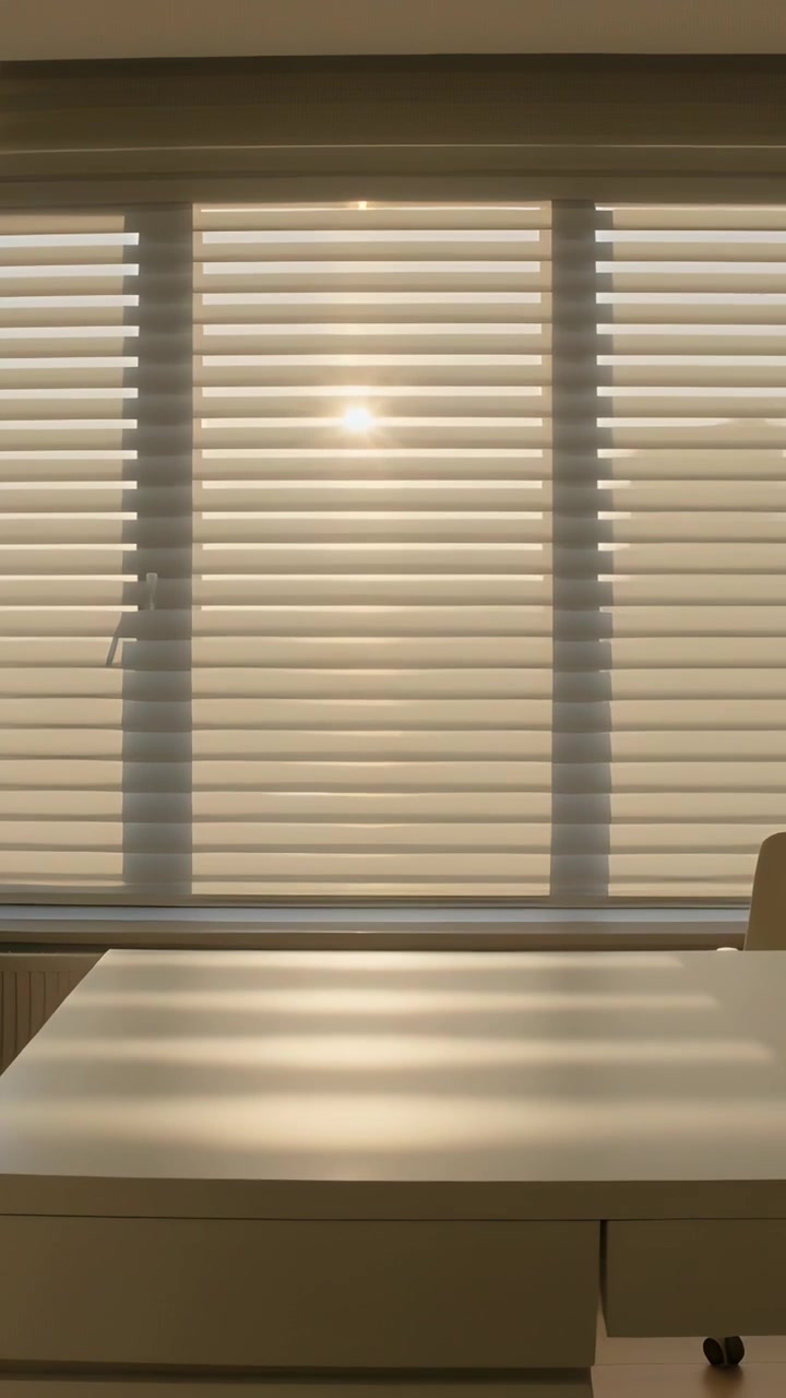 Vertical video: Shifting sunlight passing through roller blind, casting bands across desk at study