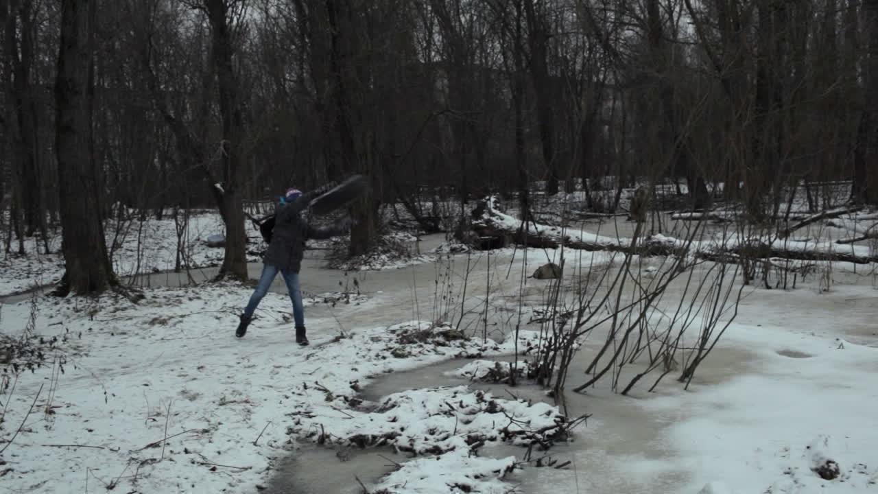 Boy teenager taking away used tire from the way in winter park