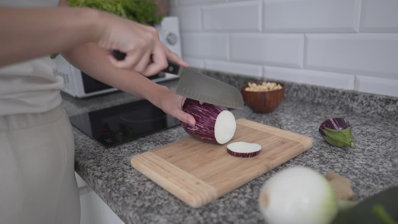 Woman Chopping Eggplant in a Kitchen