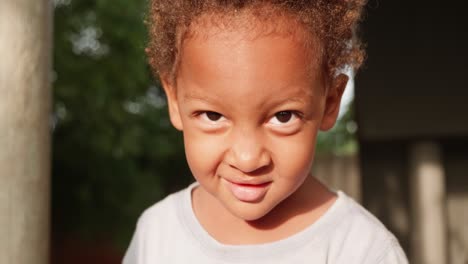 a close up shot of a young mixed raced child's face as he smirks and smiles into the camera