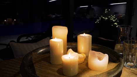 The-shot-of-light-candles-on-a-metal-tray-on-a-wooden-table-in-a-cozy-home-in-the-dark-evening