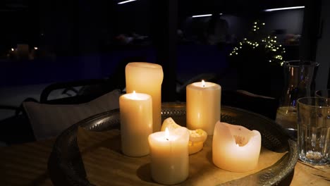 the shot of light candles on a metal tray on a wooden table in a cozy home in the dark evening