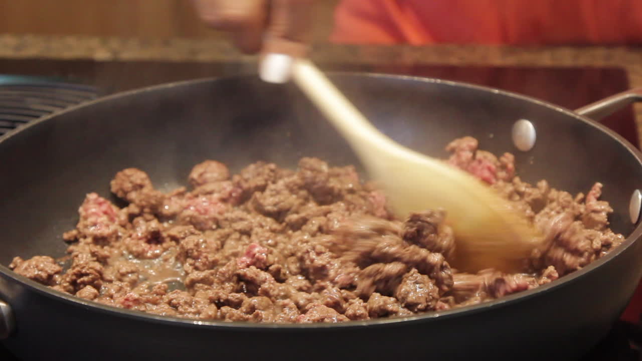 Stirring and cooking meat in a skillet, sizzling with heat and seasoning