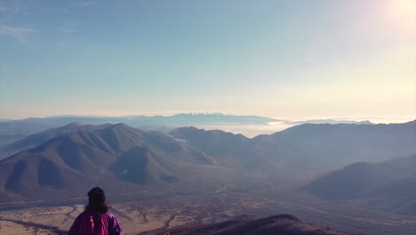 person coming to the edge of a mountain overlooking the landscape