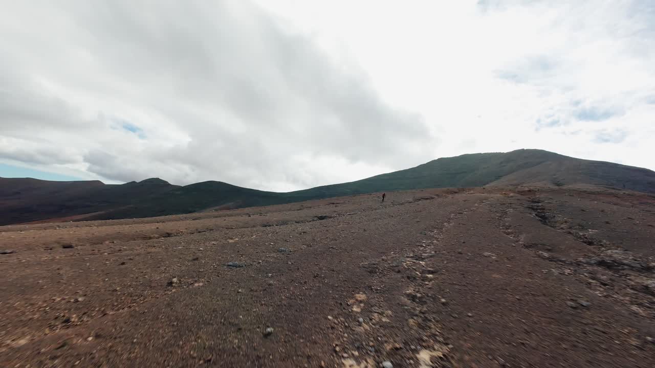 A man walks alone across the rugged volcanic landscape of Mirador de Vallebrón, Fuerteventura