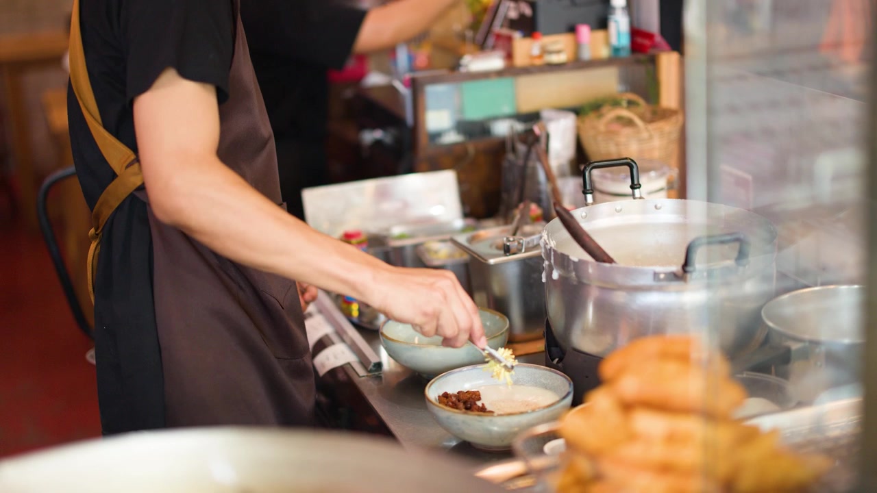 Un venditore di street food in grembiule prepara ciotole di zuppa in un mercato affollato