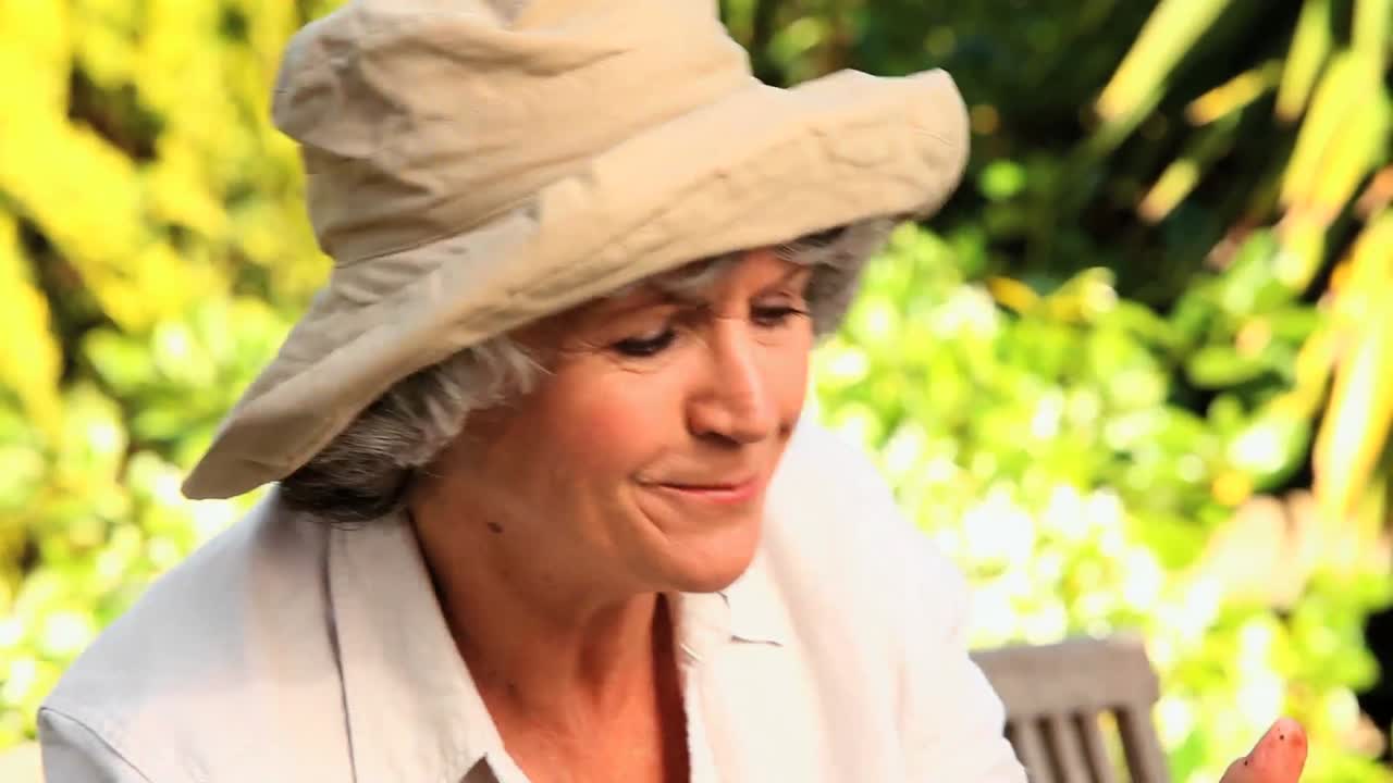 여자 가 정원 에서 식물 을  ⁇ 기고 있다