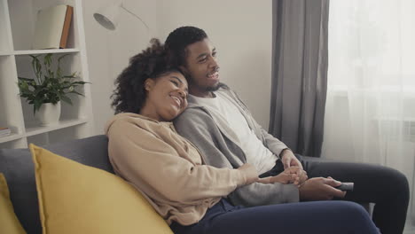 young couple laughing while watching a film