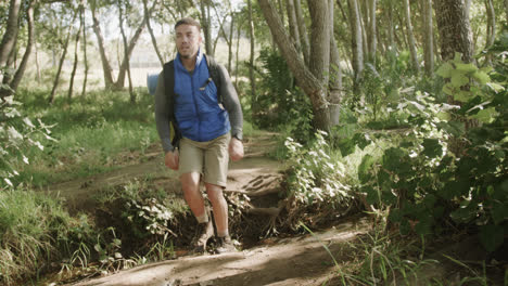 Hombre-Afroamericano-Con-Mochila-Y-Senderismo-En-El-Bosque,-Cámara-Lenta