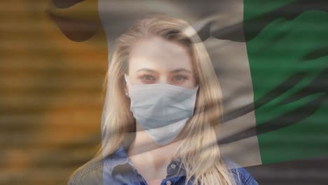 animation of flag of ivory coast waving over woman wearing face mask during covid 19 pandemic