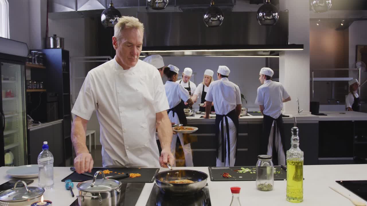 chef masculino caucásico profesional en una cocina de un restaurante preparando comida usando una sartén