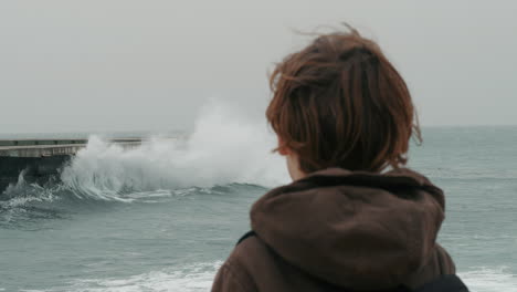 lonely boy watching broken ocean waves