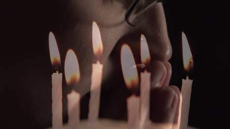 Composite video of burning candles against close up of a caucasian woman praying