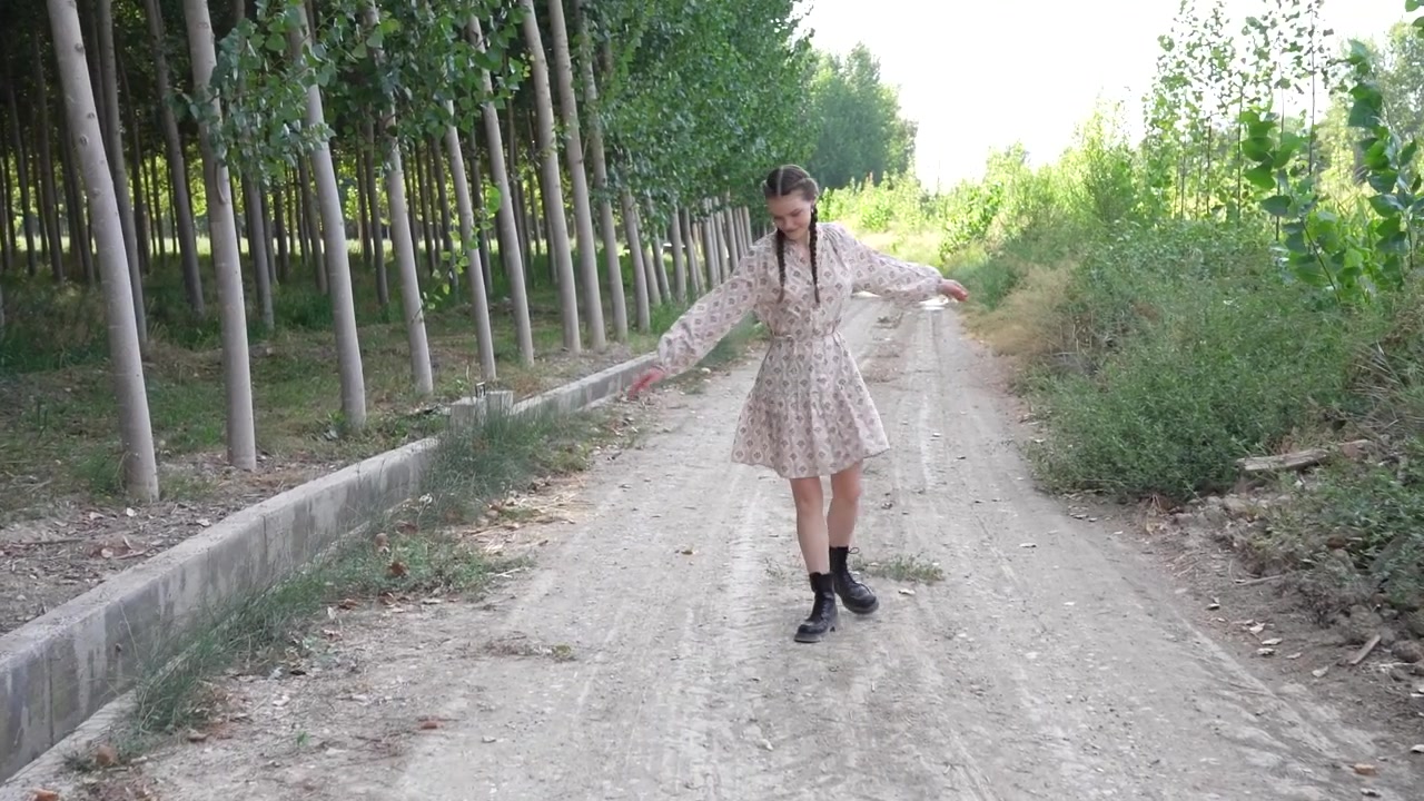 Una giovane donna gioiosa balla liberamente su un sereno sentiero di ghiaia, circondata da una natura splendida.