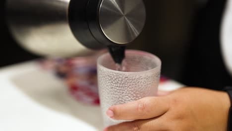 hand pouring water from kettle into glass