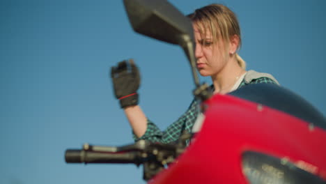 a young woman is seen preparing to ride a powerful red motorcycle, gripping the clutch lever with focus