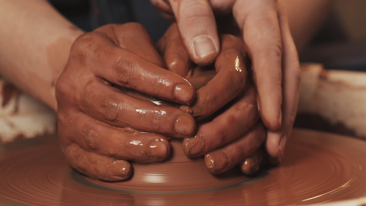 manos moldeando arcilla en una rueda de cerámica