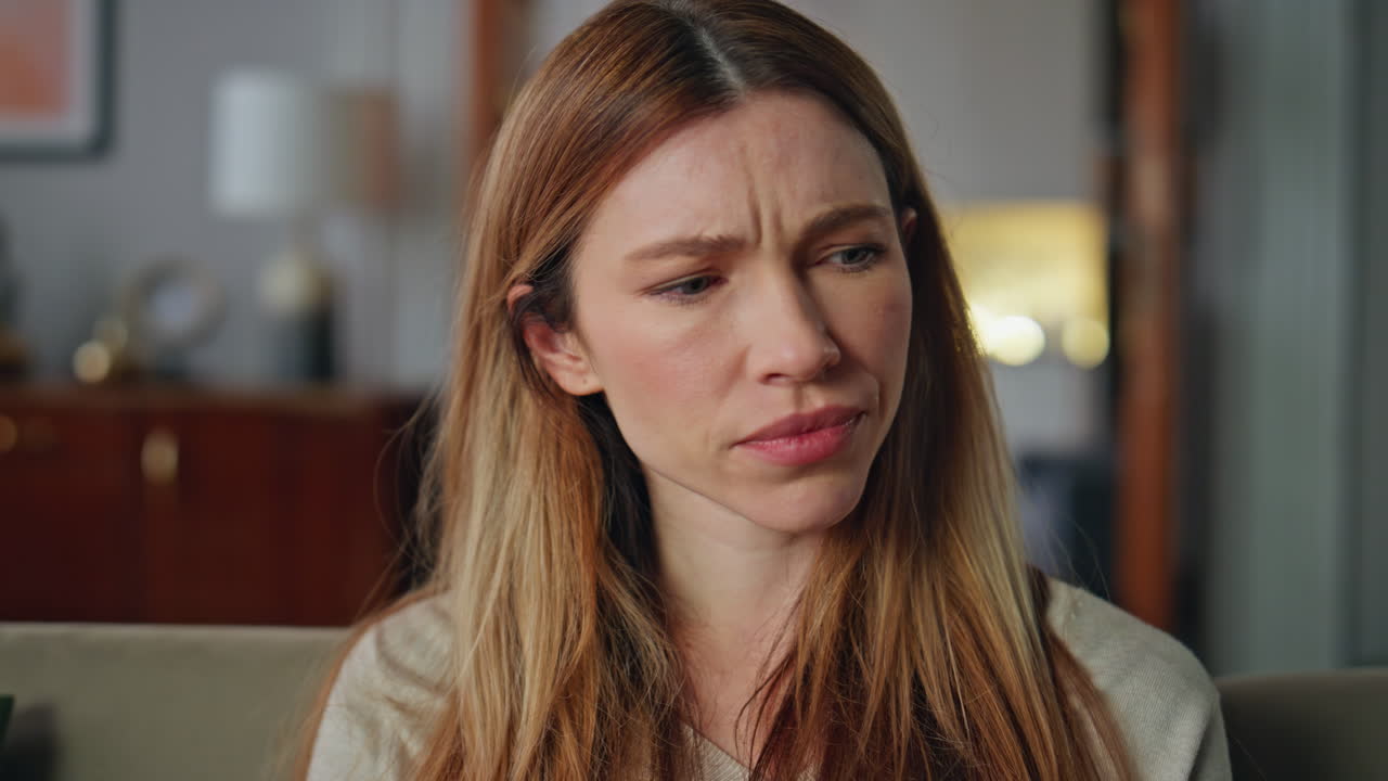 Disappointed woman sitting home couch close up. Portrait dissatisfied young girl