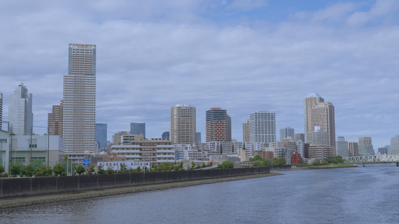 A peaceful wide shot of the Tokyo skyline with tall skyscrapers and modern buildings along the river