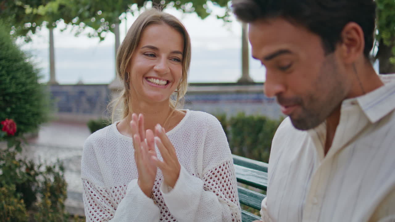 사랑스러운 여자가 벤치에서 사랑스러운 남자친구에게 선물을 준다. 사랑하는 사람들이 키스하는