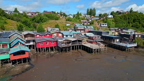 aerial orbit establishing of the colorful palafittes of castro in the big island of chiloé, low tide with humid substrate, chile