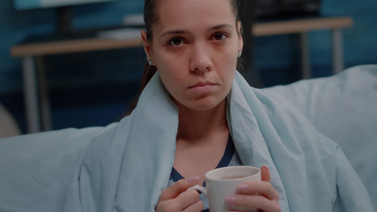 Close up of sick woman with blanket holding cup of tea