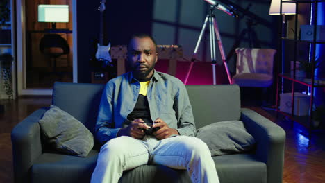 focused gamer in rgb lit home gaming with gamepad, enjoying himself