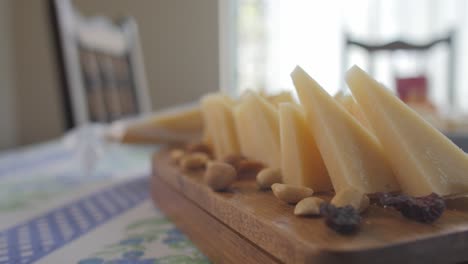 pieces of cheese and nuts on a wooden coaster on the table