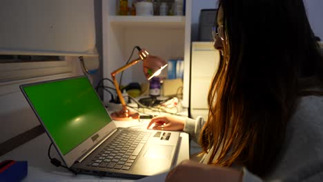 niña en una clase nocturna mostrando la tarea a través de una computadora portátil con pantalla verde