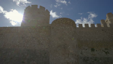 a low-angle panning view of a castle huge walls, spain.
